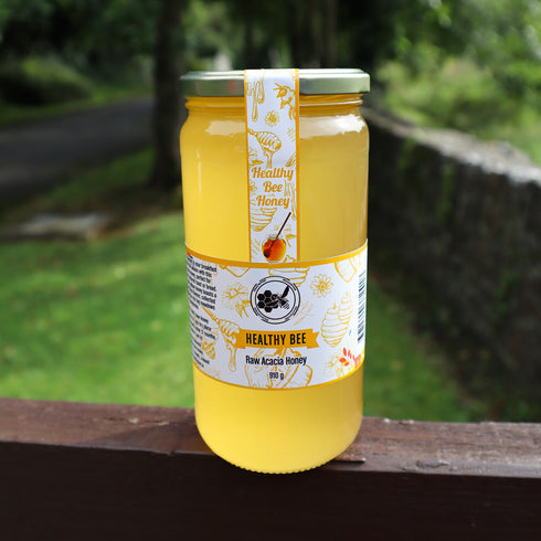Jar of honey with a 'Healthy Bee' label on a wooden surface with a natural background