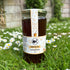 Jar of Healthy Bee Raw Chestnut Honey on grass with flowers